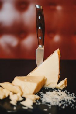 Pedaços de queijo Mozzarella sobre mesa com uma faca espetada.